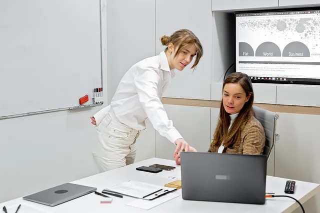 Two professionals discussing work with digital tools in a sleek modern office setting. Byråval och samarbete: så upphandlar och följer du upp en marknadsbyrå